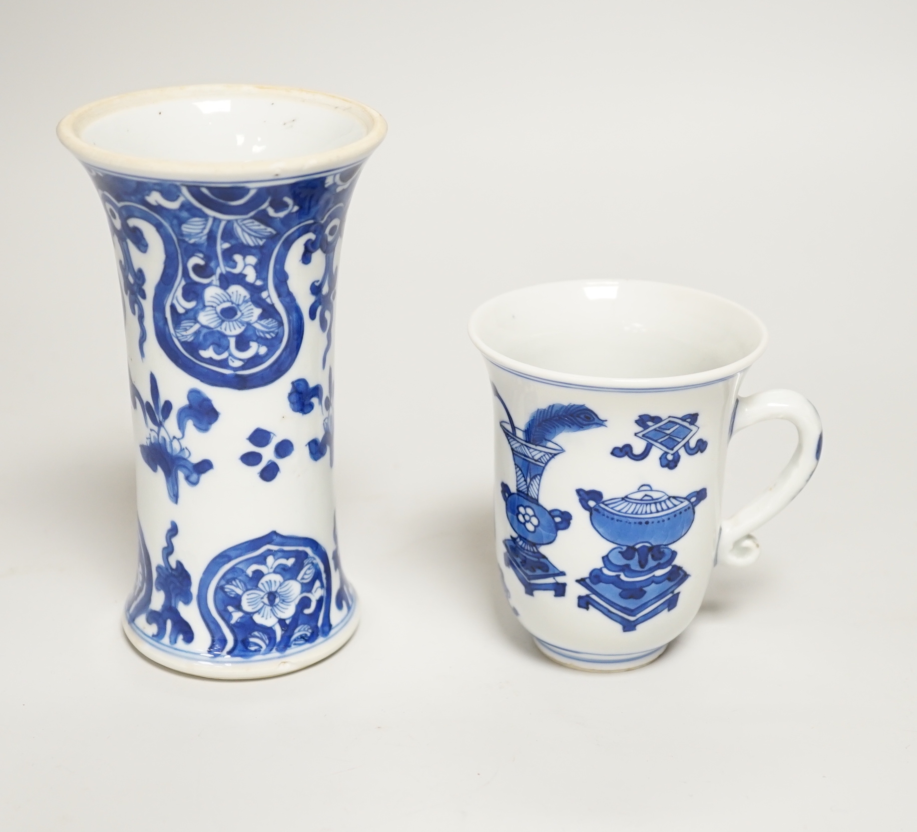 A Chinese blue and white small vase and a similar ‘Hundred Antiques’ chocolate cup, both Kangxi period, chocolate cup 9cms high